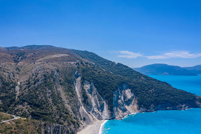 Scenic view of sea and mountains against blue sky