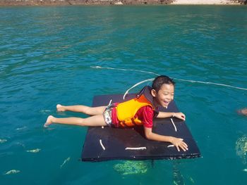 Smiling boy lying on pool raft in lake