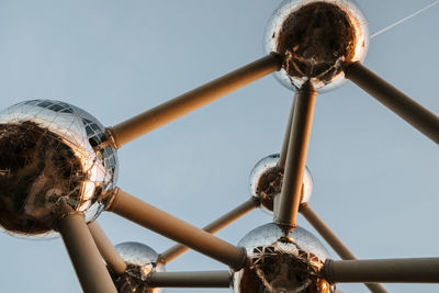 Low angle view of woman holding metal against clear sky