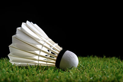 Close-up of shuttlecock on grassy field against black background