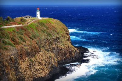 Lighthouse by sea against sky