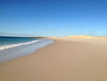 Scenic view of beach against clear blue sky