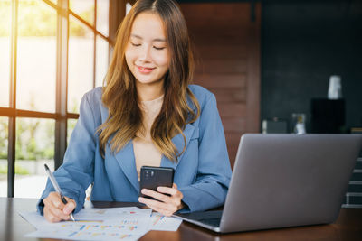 Portrait of young woman using laptop at office