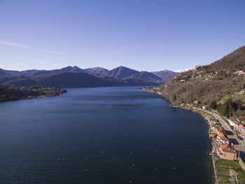 Scenic view of sea and mountains against clear blue sky