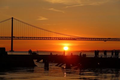 Silhouette people on suspension bridge during sunset