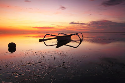 Silhouette boat on beach against sky during sunset