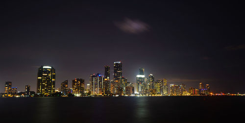 Illuminated buildings in city against sky at night