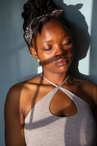 Portrait of beautiful young woman with her eyes closed against the window shadows on her face 