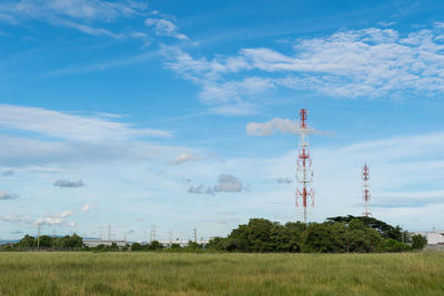 Communications tower on field against sky
