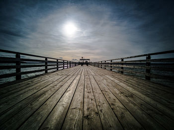 Surface level of footbridge on pier against sky