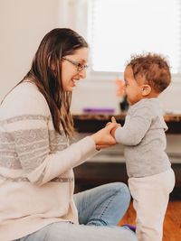 Smiling mother playing with son at home