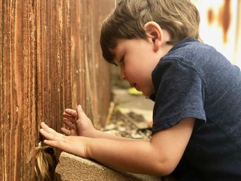 Cute boy looking at dog against wall