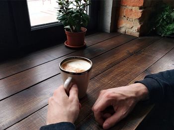 Close-up of man holding coffee cup on table