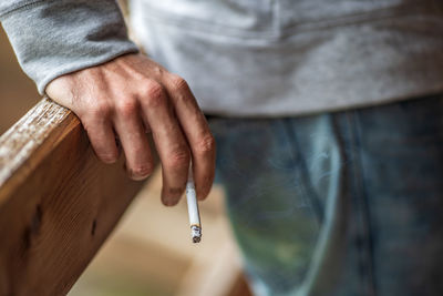 Midsection of man holding cigarette