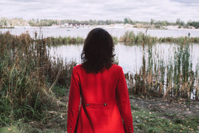 Rear view of woman standing by lake