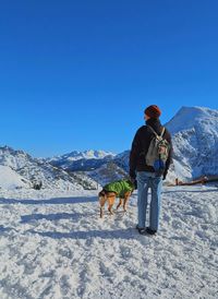 Rear view of man walking on snow covered landscape