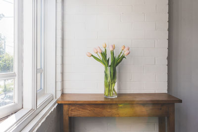 Flower vase against window at home