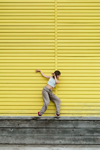 Full length of man standing against yellow wall