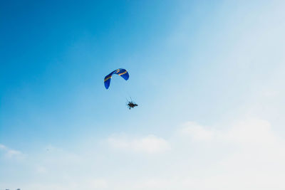 Low angle view of paragliding against blue sky