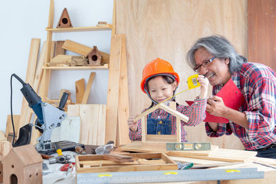 Girl with grandfather making model house at workshop