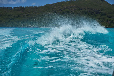 Waves splashing in sea against mountain