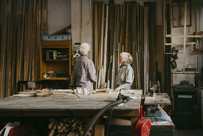 Male and female senior entrepreneurs looking at wood in workshop