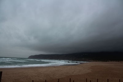 Scenic view of beach against cloudy sky