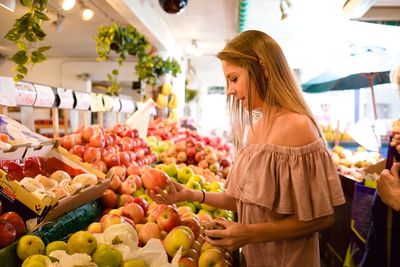 Side view of woman buying fruits at market