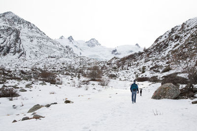 People on snowcapped mountains against clear sky