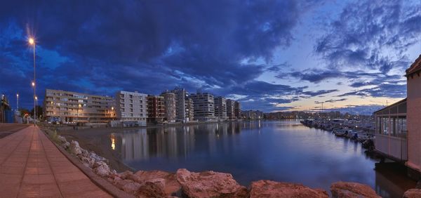 Panoramic view of canal amidst buildings against sky at dusk