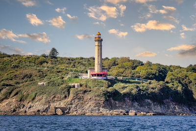 Lighthouse by sea against sky