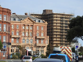 Cars on road by buildings against sky in city