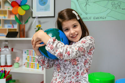 Female student hugging a handmade globe world at ecology classroom