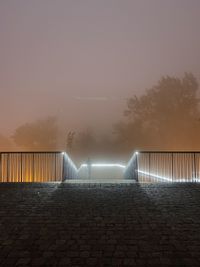 Footpath by illuminated bridge against sky at night