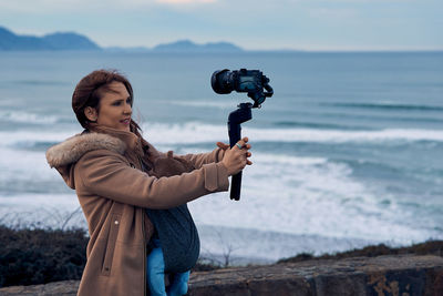 Man photographing woman standing on beach