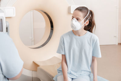 Woman wearing mask sitting at hospital