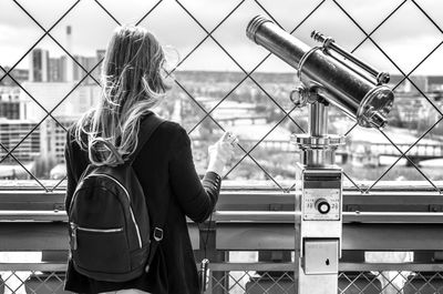 Rear view of a woman standing by a telescope on the eiffel tower, paris