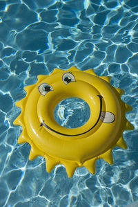 High angle view of yellow inflatable ring floating on swimming pool