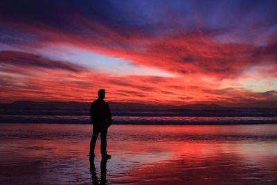 Full length rear view of man standing at beach during sunset