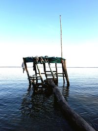 Wooden pier on sea against clear sky