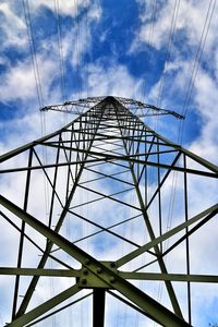 Low angle view of electricity pylon against blue sky