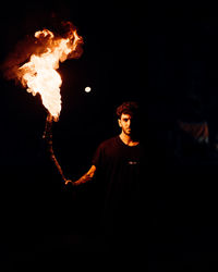 Young man with arms outstretched against black background