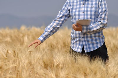 Midsection of woman standing in wheat field