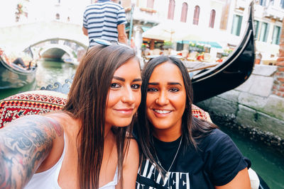 Portrait of smiling young sisters sitting in gondola