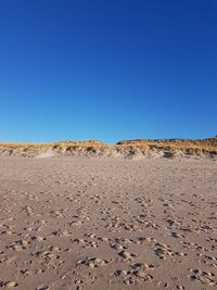 Scenic view of desert against clear blue sky