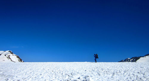 Man on snowcapped mountain against clear blue sky