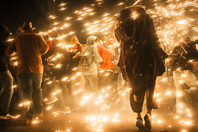 People amidst firework sparks at night