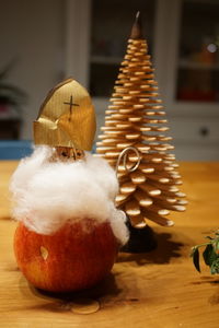 Santa claus made of apple by popsicle stick christmas tree on table