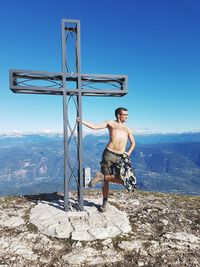 Full length of shirtless man on mountain against sky