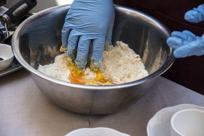 Cropped hands preparing food in bowl on table